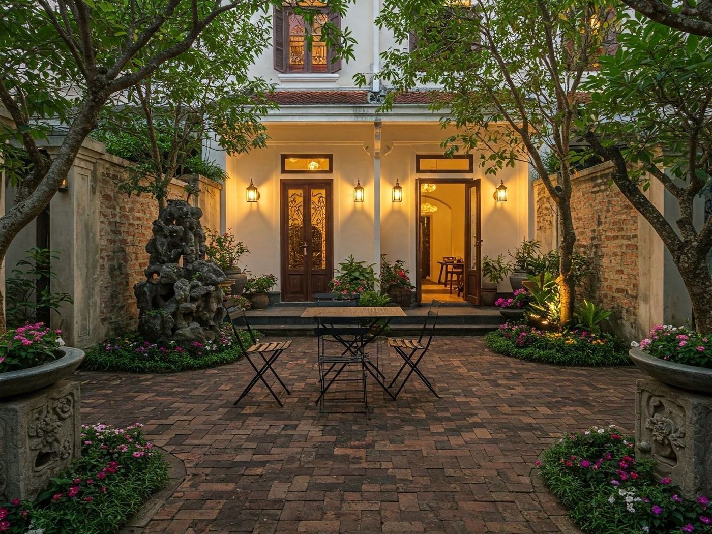 Brick-paved courtyard garden glowing with lantern light at dusk